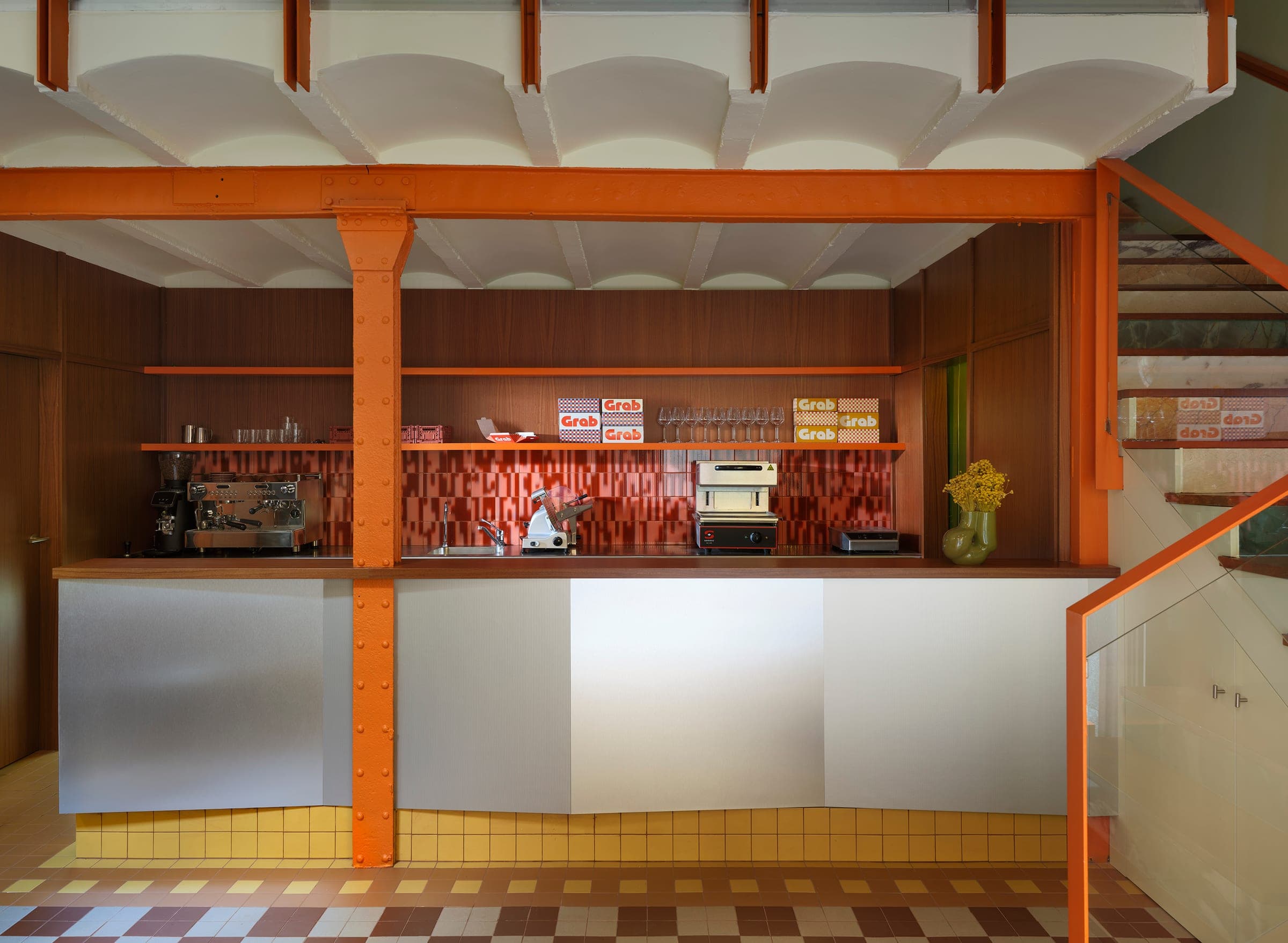Barra del restaurante Grab en Madrid — estructura industrial naranja y máquina de café